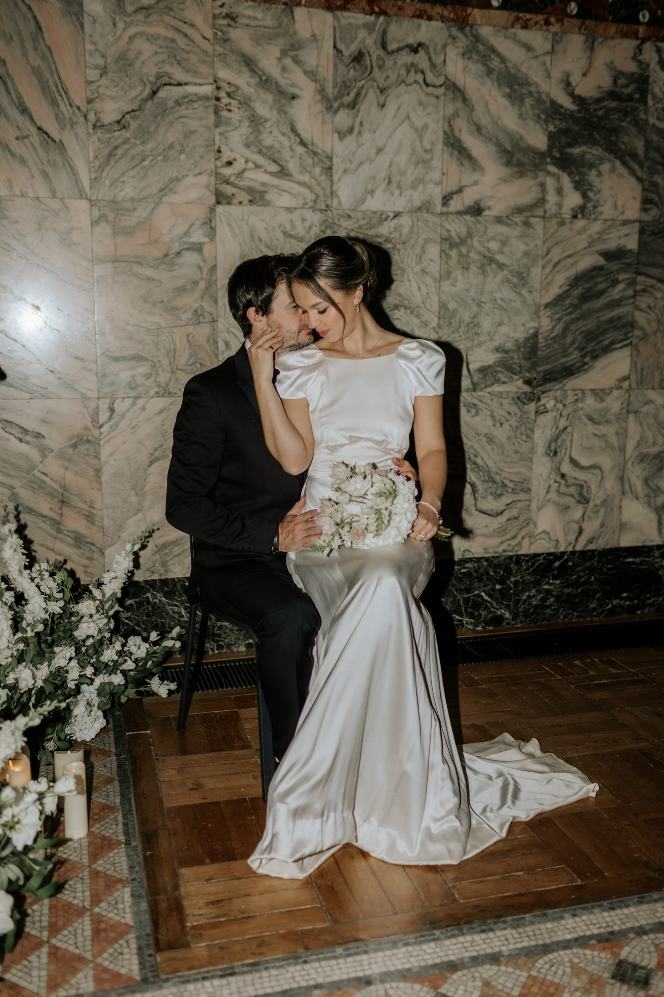 Bride sitting on her groom’s lap as they share a tender moment at the Fitzrovia Chapel in London